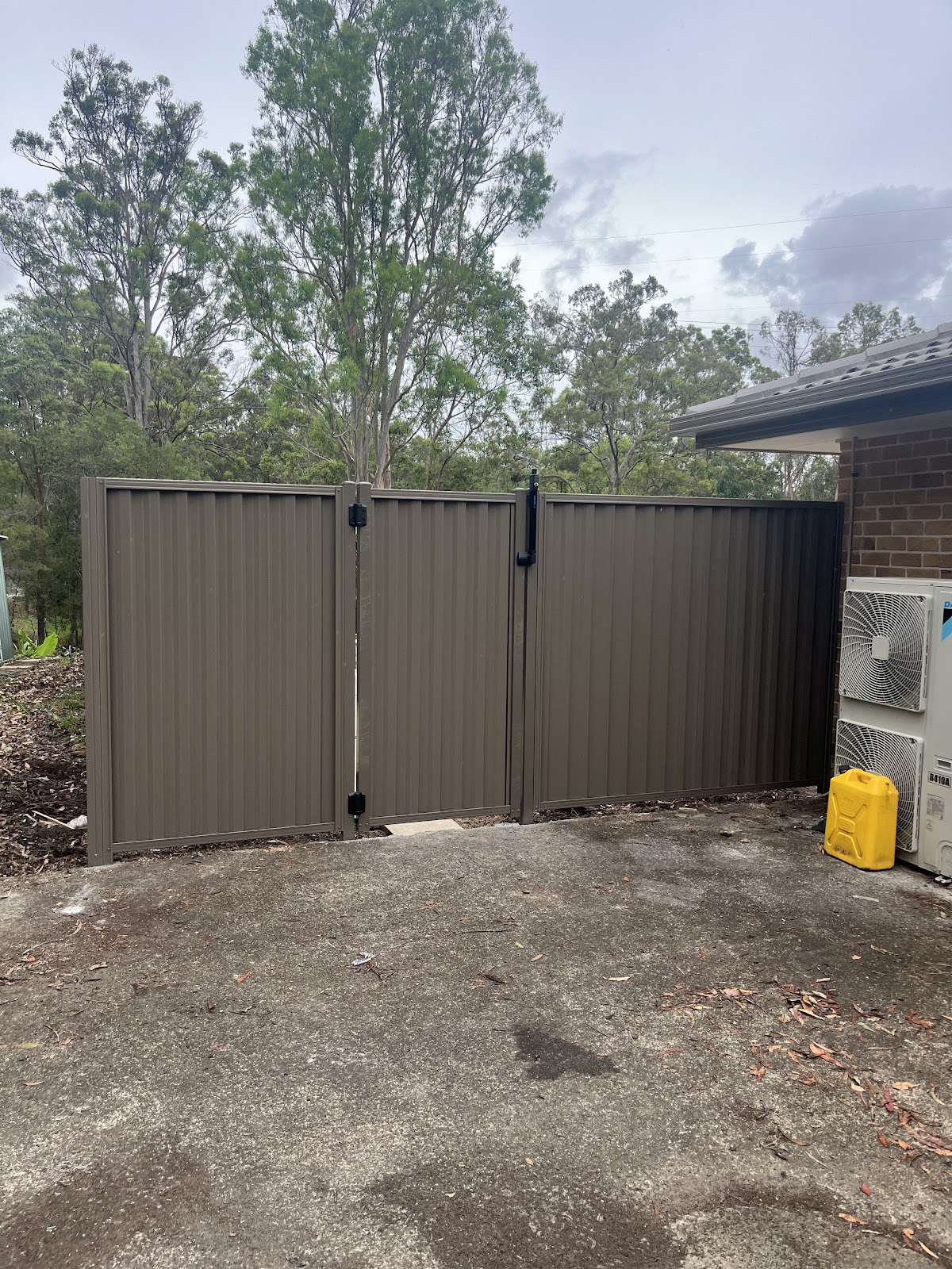 Beige steel double driveway gates beside a brick house