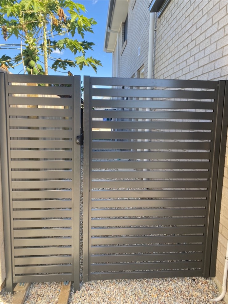 Dark aluminium horizontal slat double gate on a gravel path
